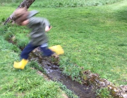 child jumping in rainboots