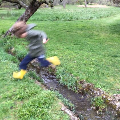 child jumping in rainboots
