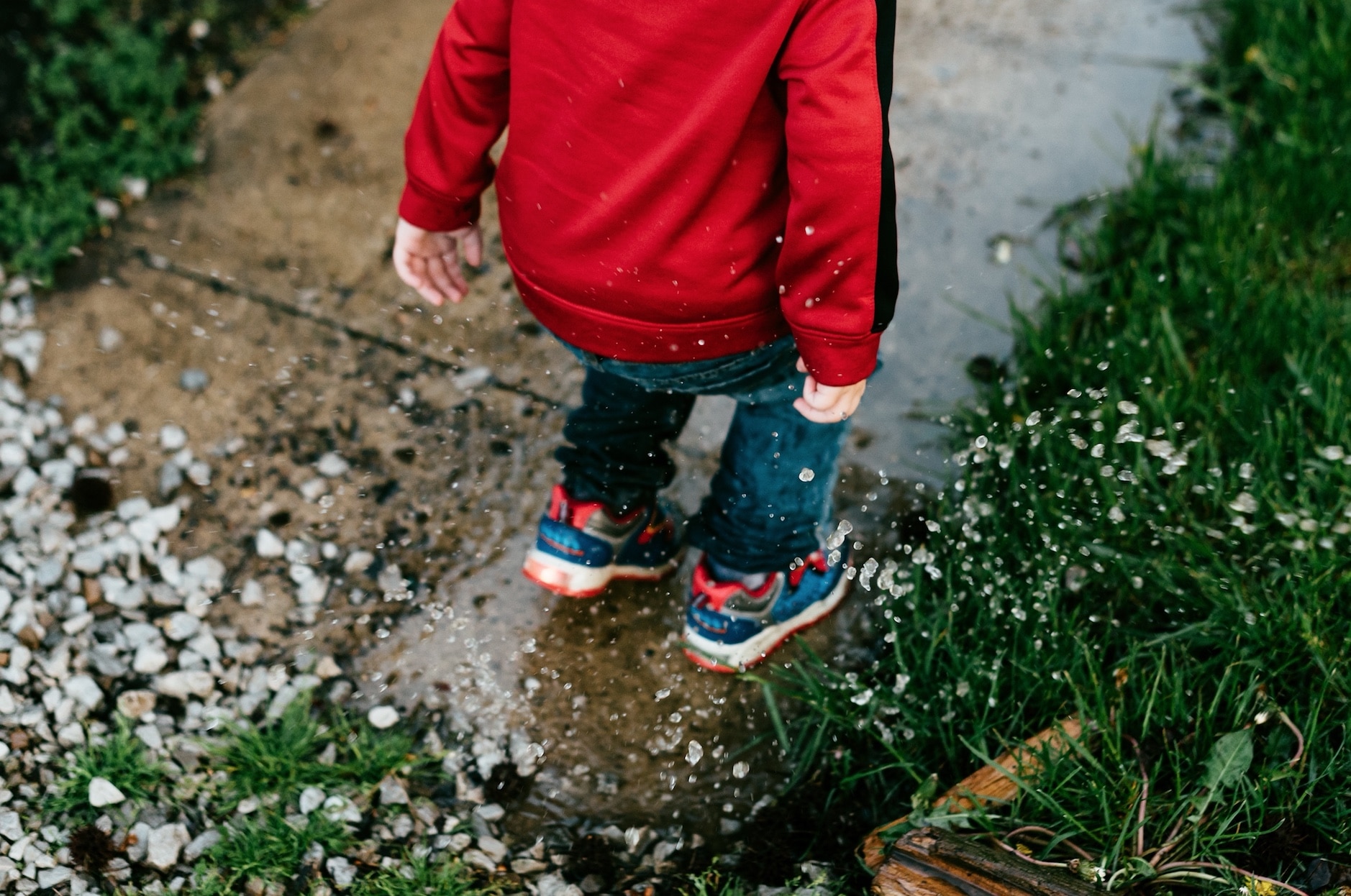children splashing in puddle outside