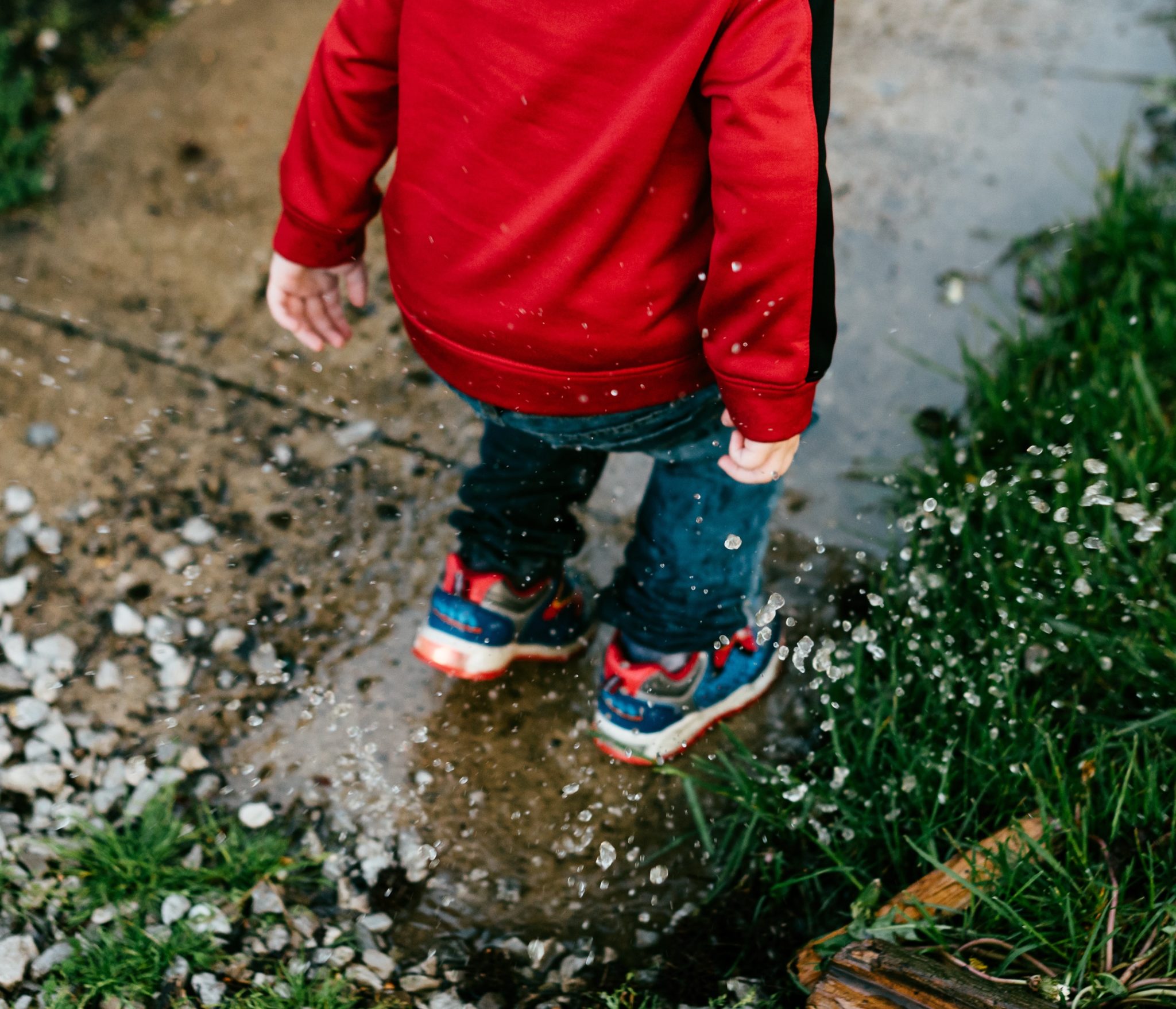 child splashing in puddle