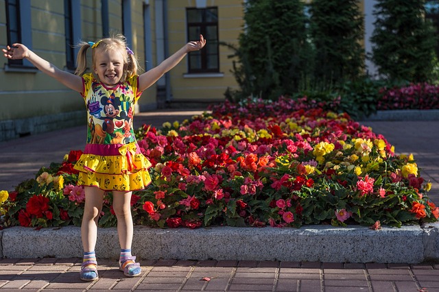 little girl standing in front of flowers